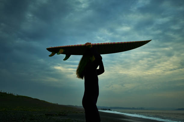 istock Senior woman surfer with surfboard before sunrise 1011137688