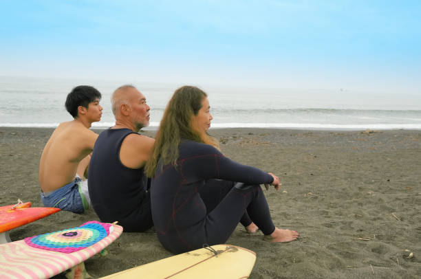 서퍼 가족 일출 전에 서핑 보드와 함께 앉아 - beach women joy sand 뉴스 사진 이미지