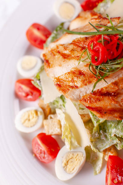 istock Caesar salad with quail eggs, cherry tomatoes, Parmesan cheese and grilled chicken in white plate on light table. 1011138250