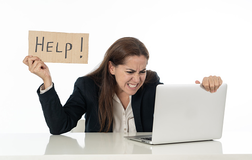 Young attractive latin woman showing help sign desperate suffering stress at work while sitting at office laptop computer desk in business overwork female feeling stressed and overwhelmed.