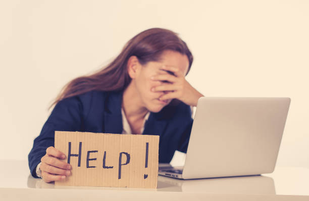 istock Young attractive latin woman showing help sign desperate suffering stress at work while sitting at office laptop computer desk in business overwork female feeling stressed and overwhelmed. 1011151240