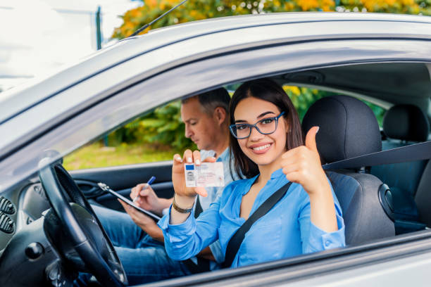 istock She looking sitting in car, looking at camera and holding driving license in hand 1011165906