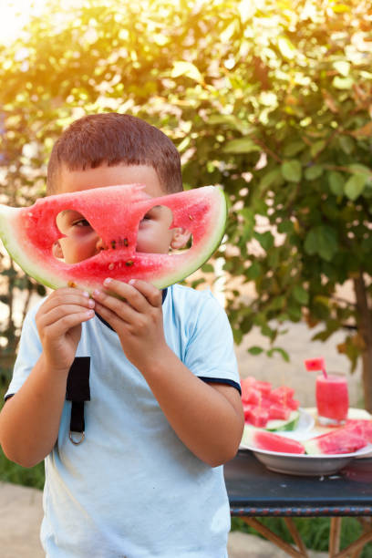 istock Summer time concept. Boy look through watermelon 1011166196