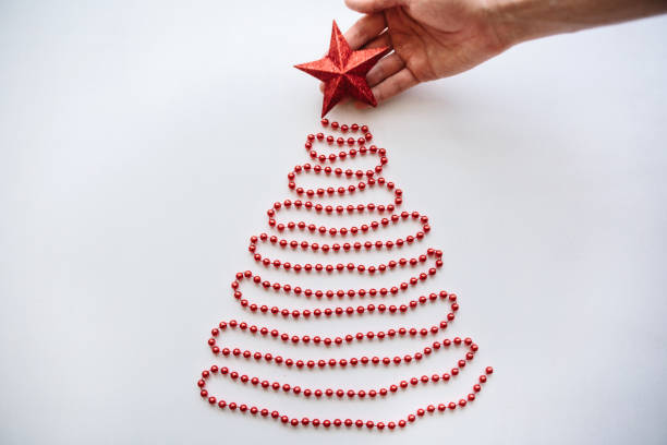 una persona hace un creativo árbol de navidad o año nuevo de granos en un estilo minimalistico y adorna con una estrella - mano sobre cadera fotografías e imágenes de stock