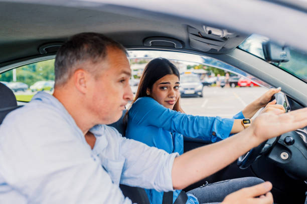 istock Beautiful young woman learning how to drive car together with her instructor 1011173194