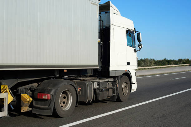 istock truck with container on the road, side view with clear blank space 1011180980