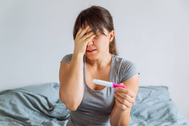 istock young pretty woman holding pregnancy test with unhappy view 1011182004