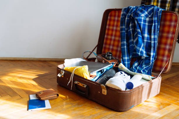 istock travel concept. suitcase with man stuff biometric passport with wallet in front. copy space 1011182402