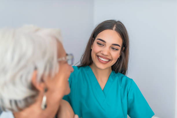 Smiling senior woman and her young pretty caregiver Young experienced doctor and older female patient. Image of elderly woman having professional medical care. Smiling senior woman and her young pretty caregiver common room stock pictures, royalty-free photos & images