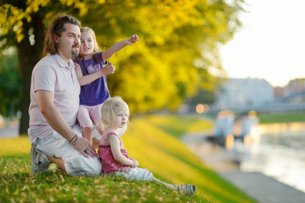 Young father and his daughters sitting by a river