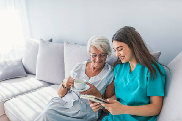 Aged elegant woman and tea time at nursing home Happy patient is holding caregiver for a hand while spending time together. Elderly woman in nursing home and nurse. Aged elegant woman and tea time at nursing home assistant stock pictures, royalty-free photos & images