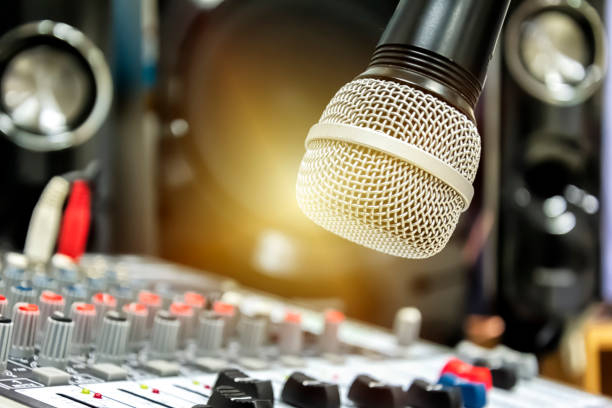 istock Hand adjusting audio mixer. The microphone is the focus. 1011190068
