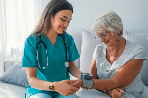 medición de la presión arterial de la mujer mayor en casa de cuidador. - female nurse fotografías e imágenes de stock