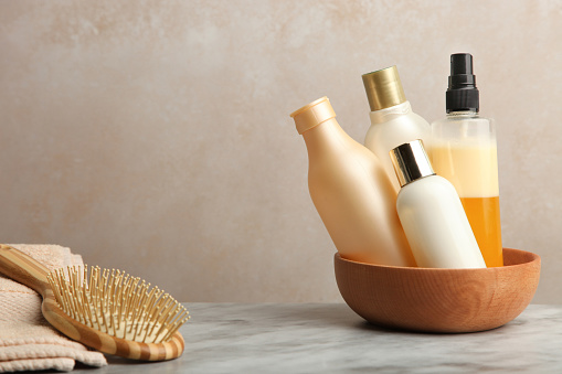 Hair care products on marble table on neutral background.