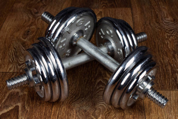 istock two iron dumbbells on a wooden floor, old school heavy dumbbell training 1011208416