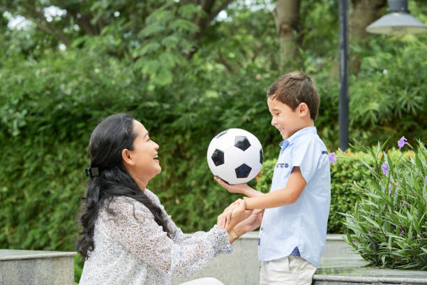 istock Asian mother supporting son with ball 1011212972