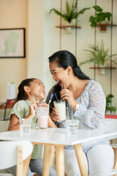 Asian mother and daughter drinking in cafe