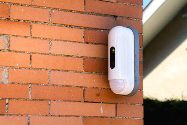 istock Surveillance Camera With Movement Detector on Red Brick House 1011215510