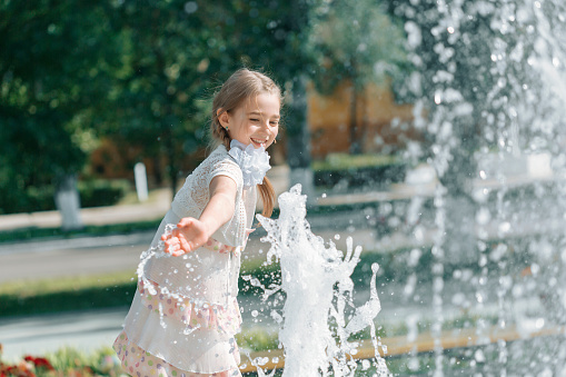 Woman having fun with water next to fountain.