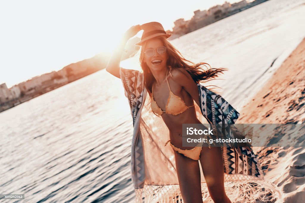 Extremely sensual. Attractive young woman smiling while standing on the beach outdoors Beach Stock Photo