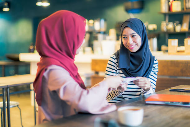 istock Malaysian Girls at a Cafe Exchanging an Envelope 1011244866