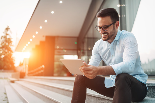 Portrait of businessman in glasses holding tablet outdoors