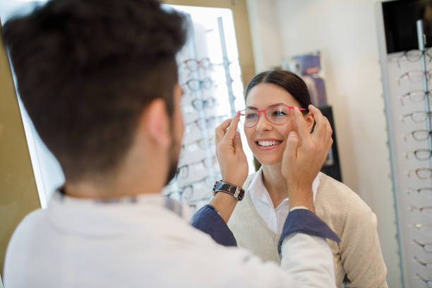 istock Selecting eyeglasses in optical store with assistance of optometrist 1011253712