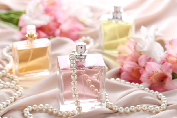 istock Perfume bottles with flowers and beads on satin background 1011254228