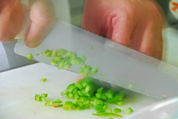 Hand with knife slicing chili