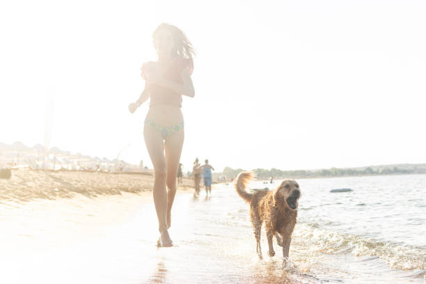 istock Woman Running With Dog in the beach 1011267366