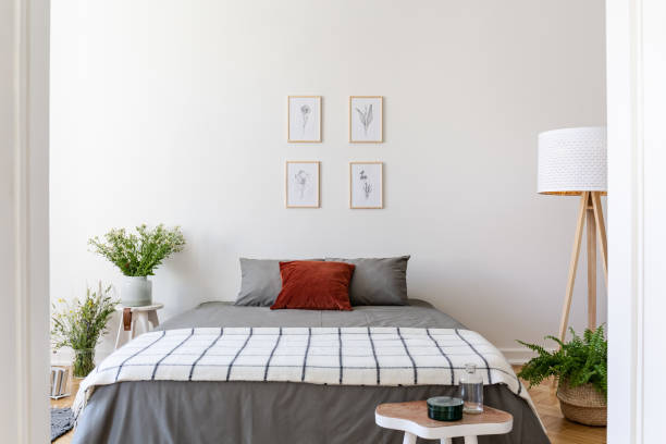 istock Posters above grey bed with patterned blanket in bedroom interior with flowers and lamp. Real photo 1011270700