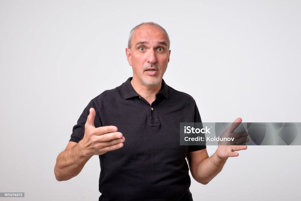 Mature hispanic man is trying to explaine his rightness. Argue with gestures. Mature hispanic man is trying to explaine his rightness. Men Stock Photo