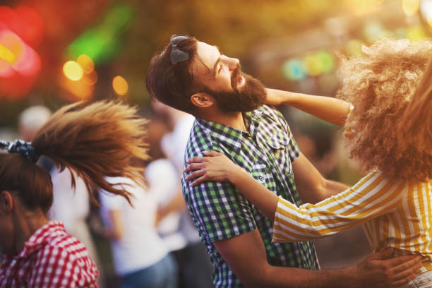 Friends dancing at a concert. Closeup side view of a couple having a country style dance at an open air concert on a summer afternoon. One more person is partially in the frame, also released. country and western stock pictures, royalty-free photos & images