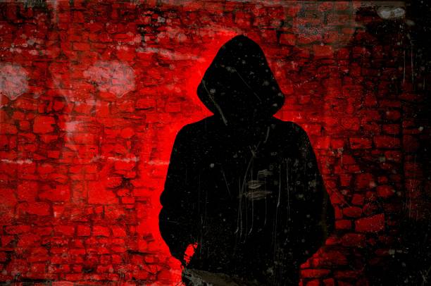 istock Male figure with hood on red wall background. Hacker concept. 1011280078