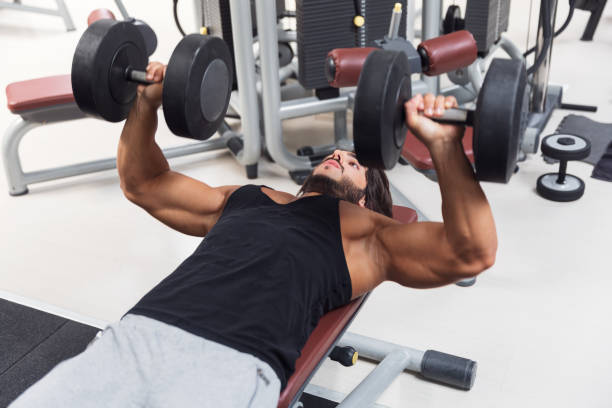 Bodybuilder lifting dumbbell weights in a gym stock photo