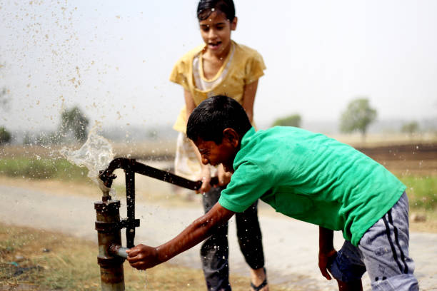 Rural children drinking water outdoor in the nature.