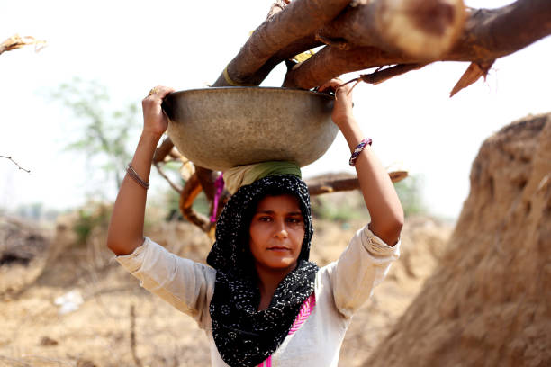 istock Rural women carrying woods on her head 1011284122