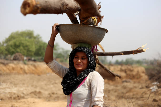 istock Rural women carrying woods on her head 1011284126