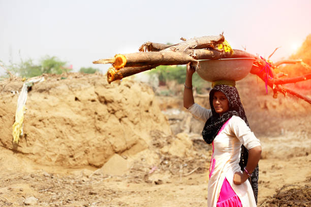 istock Rural women carrying woods on her head 1011284128