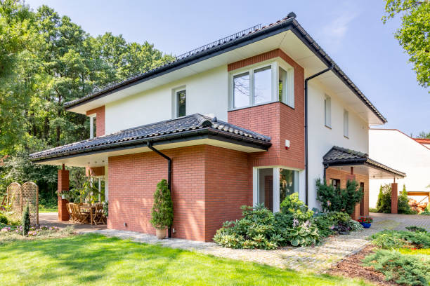 istock Red brick house with terrace and green grass and trees during summer 1011284748