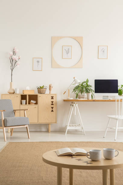 istock Posters on white wall above desk with computer desktop next to cabinet in flat interior. Real photo 1011288112