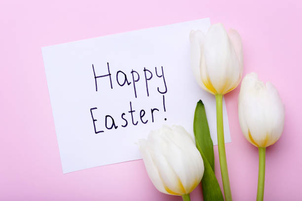 istock Inscription Happy Easter with white tulips on pink background 1011288614
