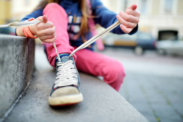 Cute little girl learning to tie shoelaces outdoors Cute little girl learning to tie shoelaces outdoors on summer day child tied up stock pictures, royalty-free photos & images