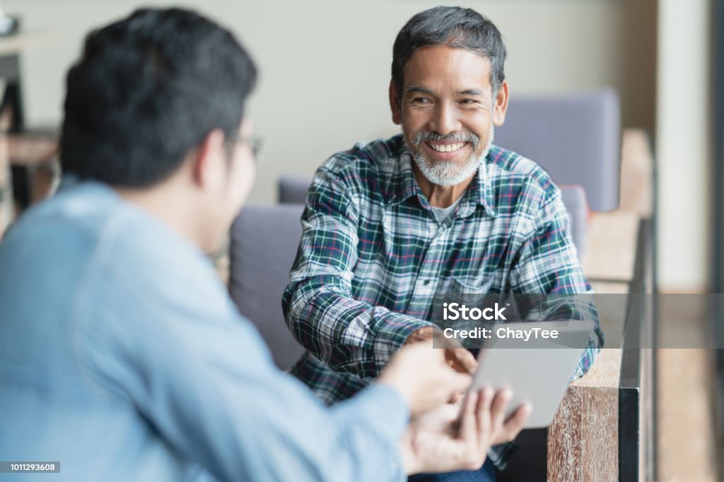 古い短いひげ男性に座って、笑顔とスマート デジタル タブレットに表示プレゼンテーションをパートナーに耳を傾ける幸せ。ソーシャル メディアの技術指導や都会のライフ スタイルのコン - シニア世代のロイヤリティフリーストックフォト
