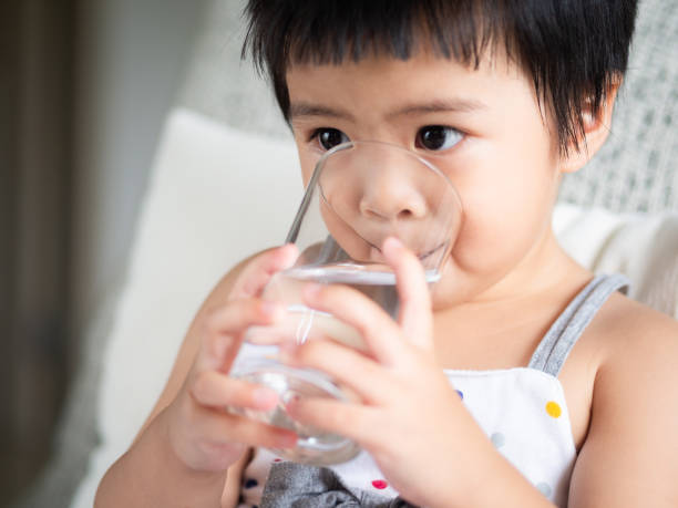 happy little cute girl holding a glass and drinking the water. children drink healthy concept. - milk child drinking little girls imagens e fotografias de stock