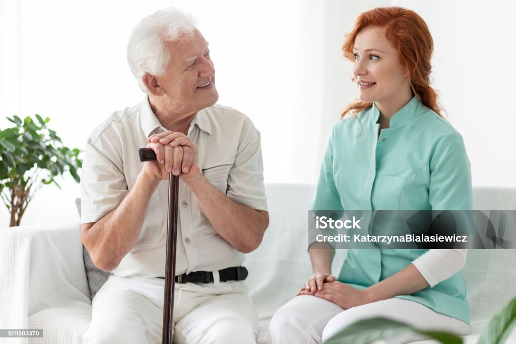 Freundliche Krankenschwester im Gespräch mit älteren Mann mit Gehstock lächelnd - Lizenzfrei Alzheimer-Krankheit Stock-Foto