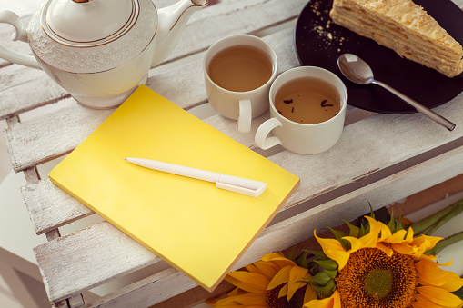 A summer romantic breakfast for two people from tea, cake and sunflowers. Plan and write down