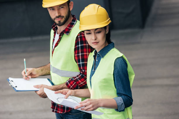 istock engineers in hardhats working with blueprint and clipboard on roof 1011317068