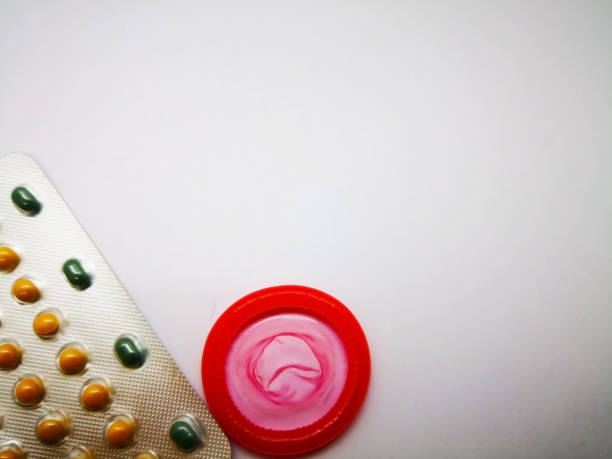 concept de médicaments et de soins de santé. médicament contraceptif oral en argent blister et préservatif rouge, contrôle des naissances. notion de problème de l’avortement. isolé sur fond blanc, mise au point sélective et l’espace de la copie - contraceptive sex education birth control pill condom photos et images de collection