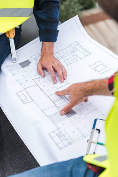 istock cropped view of engineers working and pointing at blueprint 1011331830